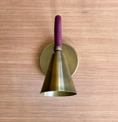 a wall mounted light on the side of a wooden wall with a purple cord hanging from it