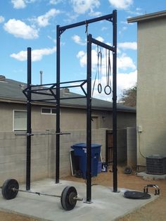 an outdoor gym in front of a house with two pull up bars on the ground