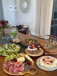 a wooden table topped with lots of different types of plates and bowls filled with food