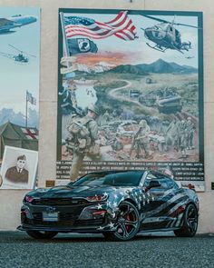 a car parked in front of a wall with pictures on it and an american flag