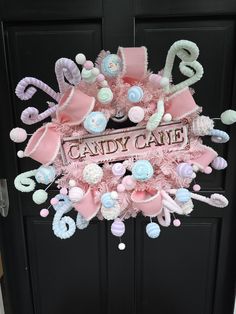 a pink candy cane wreath hanging on the front door of a house that says candy cane