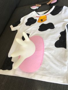 a cow shirt sitting on top of a couch next to a white mannequin