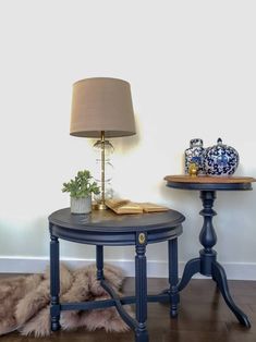 a table with a lamp on it next to another table that has a vase and potted plant on it