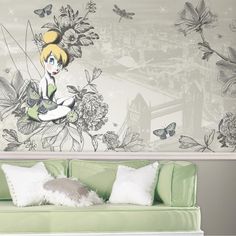 a living room with a green couch and flower wall mural on the wall behind it