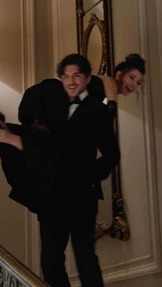 a man in a tuxedo is walking down the stairs with his arm around a woman's back