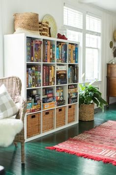 a living room filled with lots of books on top of a book shelf next to a window