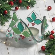 a glass bowl sitting on top of a wooden table next to christmas decorations and greenery