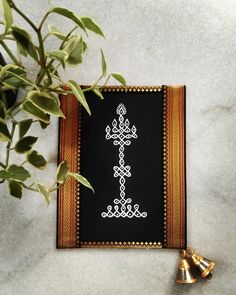 a black and gold framed cross with bells on the floor next to some green plants