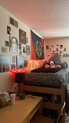 a bed room with a neatly made bed next to a desk and pictures on the wall