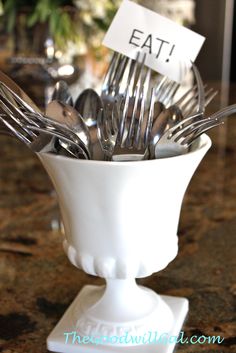 forks and spoons in a white bowl with an eat sign on the fork holder