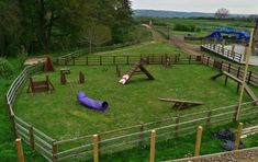 a purple tube is in the middle of a grassy area with wooden fences and playground equipment