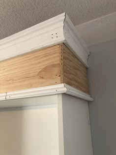 an unfinished piece of wood sitting on top of a white shelf next to a wall