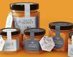 honey jars with labels on them sitting next to each other in front of an orange background