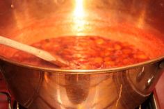 a large pot filled with lots of food on top of a stove next to a wooden spoon