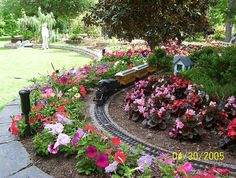 there is a toy train going through the flower garden