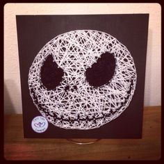 a string art skull on a black and white canvas with a purple sticker in the middle