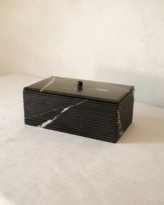 a black box sitting on top of a white bed