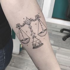 a tattoo on the arm of a woman with two scales and stars in each one