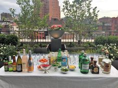 a table topped with lots of bottles and glasses on top of a white table cloth