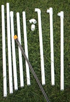 a bunch of white poles laying on top of green grass next to an orange marker