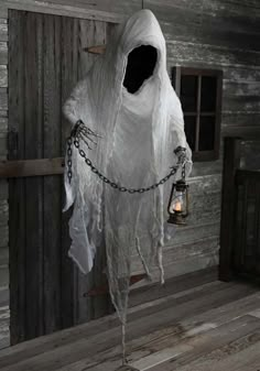 a white ghost hanging from a chain with a lantern