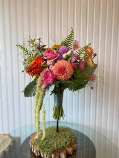 a bouquet of flowers sitting on top of a glass table in front of a wall