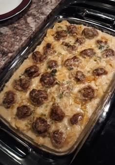 a casserole dish with meatballs and cheese in it sitting on the stove