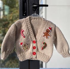 a knitted sweater hanging from a door with buttons and candy canes on it