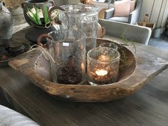 a wooden tray filled with glass vases and candles sitting on top of a table