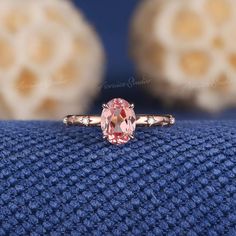 a pink diamond ring sitting on top of a blue cloth