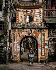 a person riding a bike in front of an old building with chinese writing on it