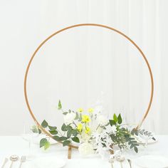 the table is set with white plates, silverware and flowers in a circular frame