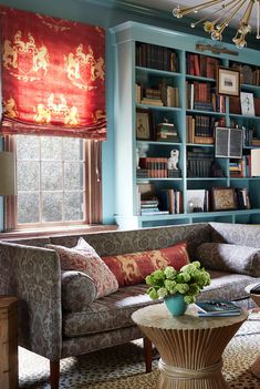 a living room with bookshelves, couches and coffee table in front of the window