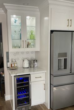 a stainless steel refrigerator and wine cooler in a kitchen with white cabinets, wood floors and hardwood flooring