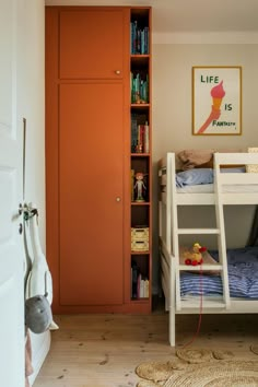 there is a bunk bed in the room with bookshelves on the wall and an orange door behind it