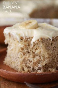 a close up of a banana cake on a plate with frosting and sliced bananas