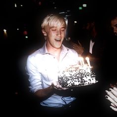 a man holding a cake with candles in it