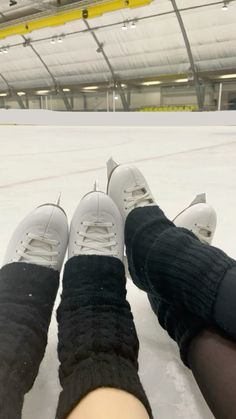 two people sitting in the snow with their feet on each other's legs, wearing black and white tennis shoes