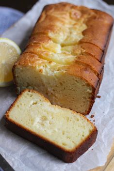 a loaf of lemon pound cake sitting on top of a piece of wax paper next to a slice of lemon