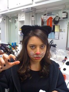 a woman with cat's face painted to look like she is pointing at the camera