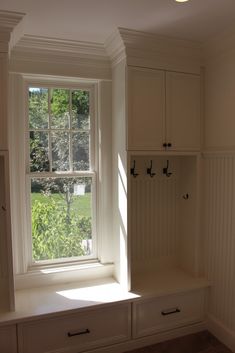 the sun shines through an open window in a room with white cabinets and drawers