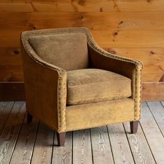 a brown chair sitting on top of a wooden floor next to a wood paneled wall