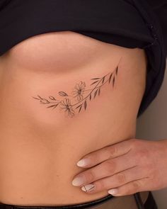 a close up of a person's stomach with flowers on the side and an arrow tattoo