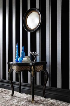 a black and white striped wall with a mirror on the end table next to it