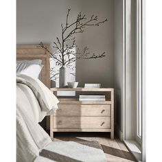 a bedroom scene with focus on the bed and nightstand, which has a tree in it