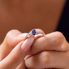 a woman's hand holding an engagement ring with a blue stone in the middle