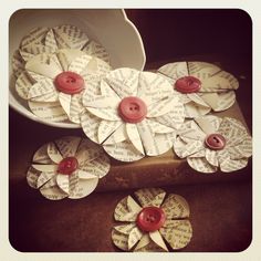 several pieces of paper that have been made into flowers with red buttons and words on them