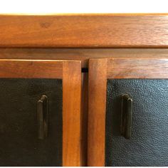 a close up of a cabinet with two doors and black leather panels on the bottom