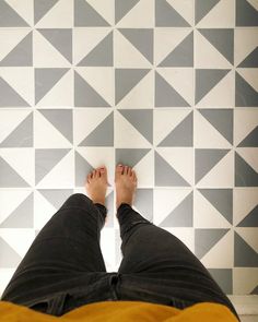 a person with their feet up on the floor in front of a geometric tile wall