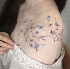 a woman's breast with blue flowers painted on the side and behind her belly